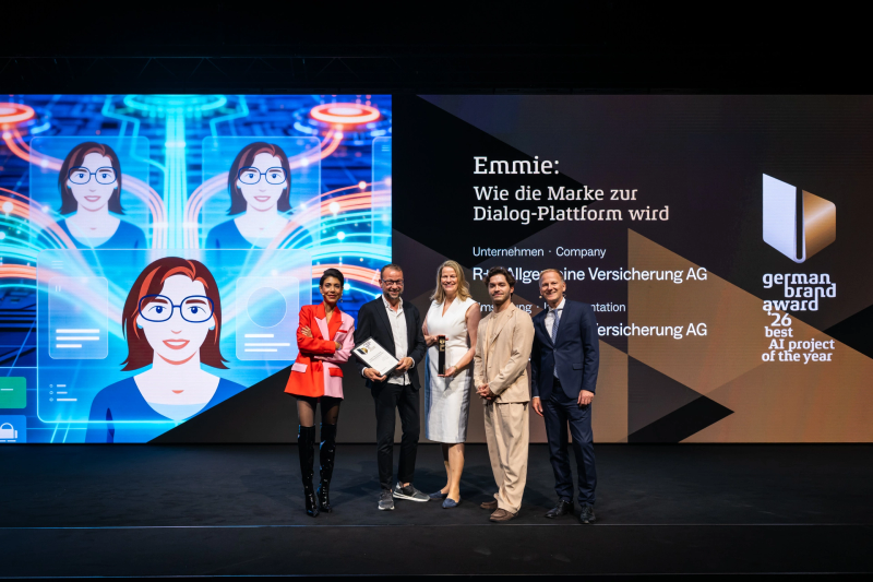 Sven Schmitt, Anke Josten and Eldin Thomas of R+V Versicherung accept the Best of Best distinction of the German Brand Award 2026 for the AI chatbot Emmie, flanked by jurors Sophia Rödiger (left) and Christian Rummel (right).