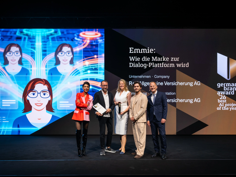 Sven Schmitt, Anke Josten and Eldin Thomas of R+V Versicherung accept the Best of Best distinction of the German Brand Award 2026 for the AI chatbot Emmie, flanked by jurors Sophia Rödiger (left) and Christian Rummel (right).