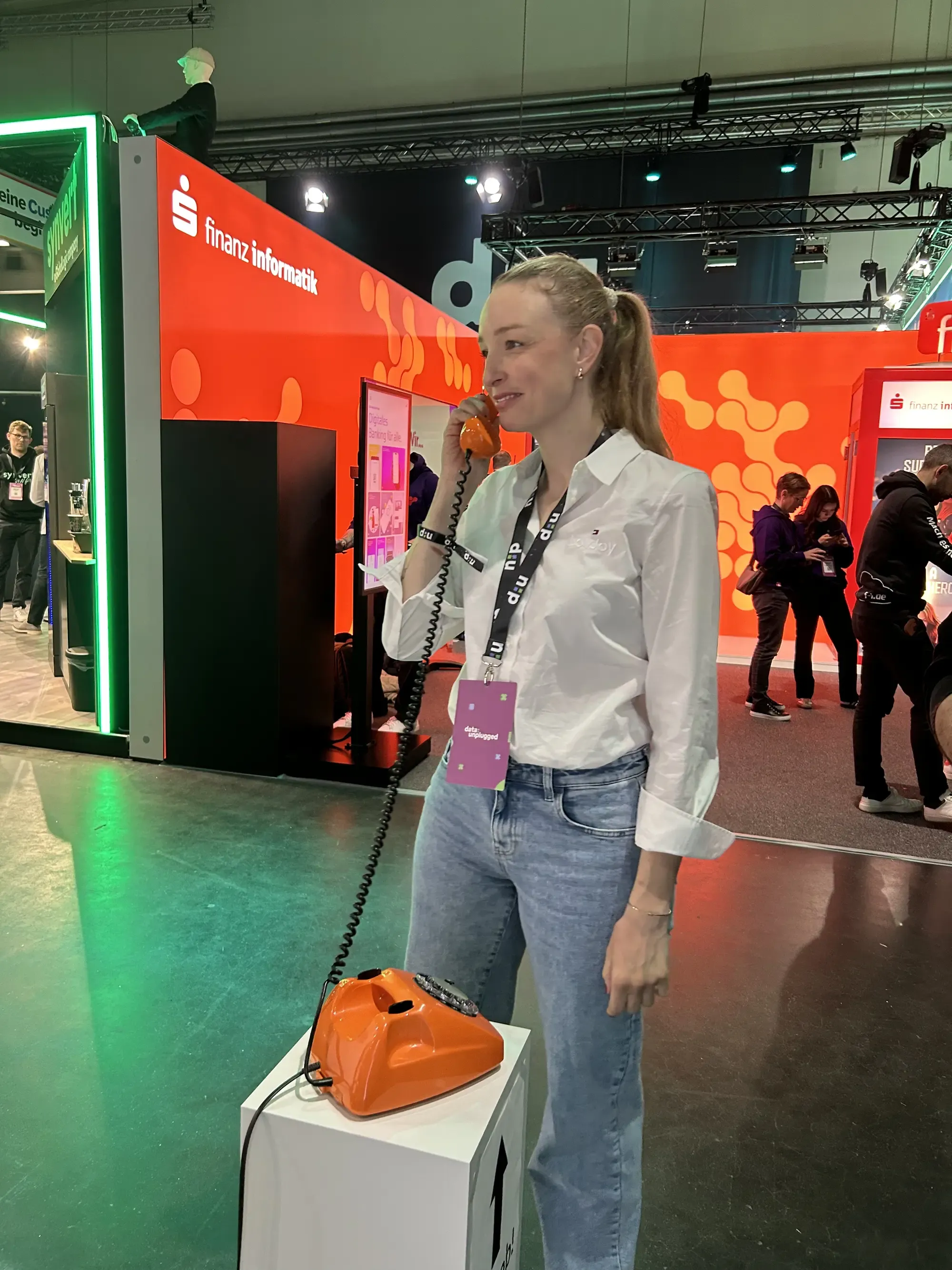 Unsere Kollegin Katharina probiert den Voice Agent mithilfe unseres orangenen Telefons aus.