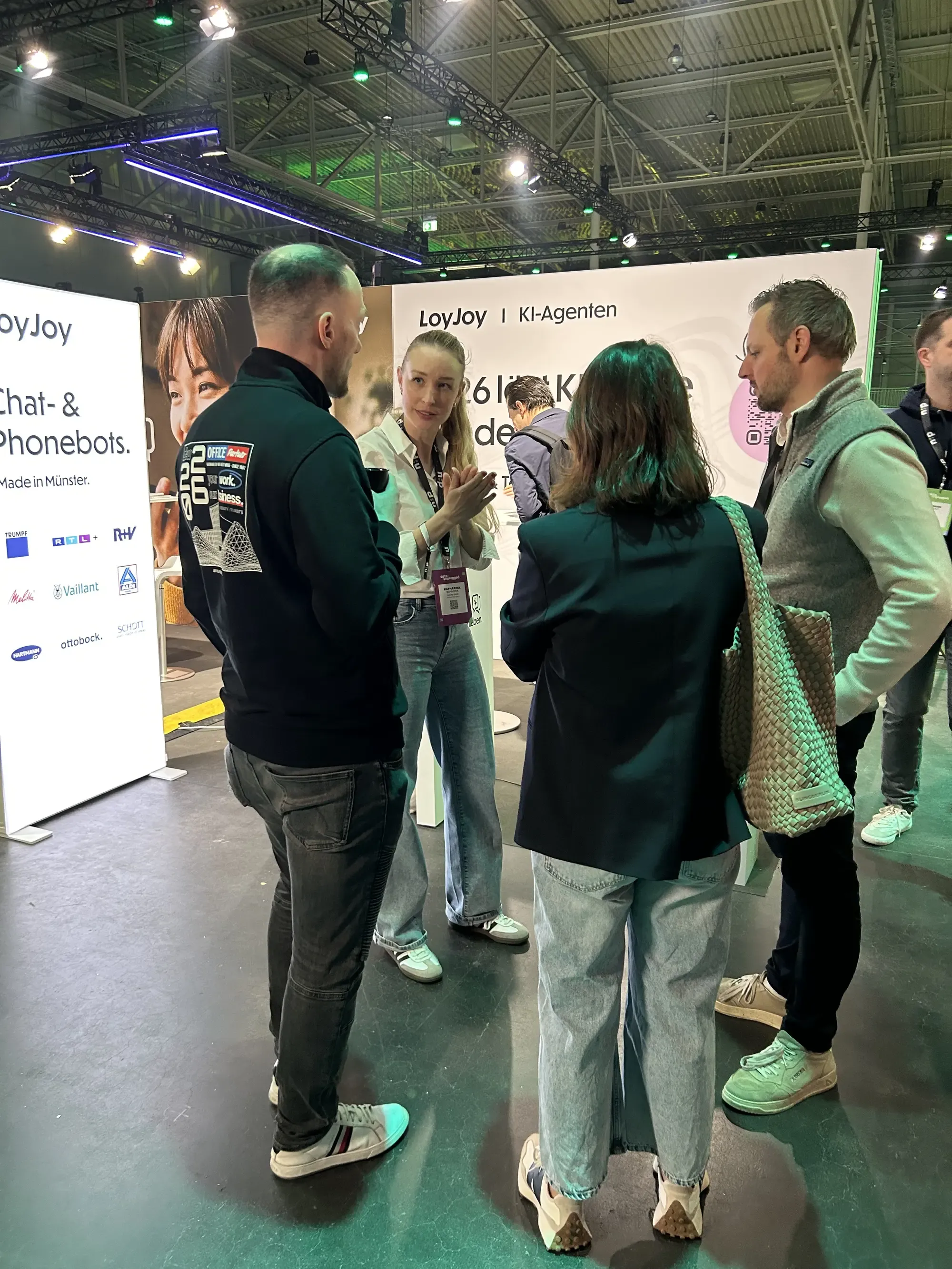 There’s a lot going on at our booth. A group of visitors is gathered at our booth, getting advice from the LoyJoy team.